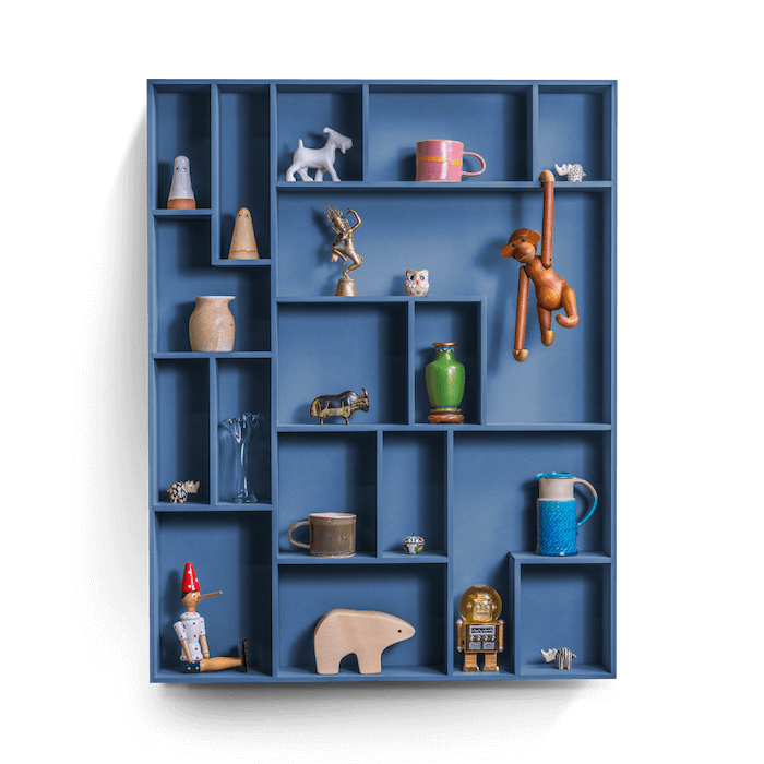 Decorative wall shelf with playful compartments displaying various items.