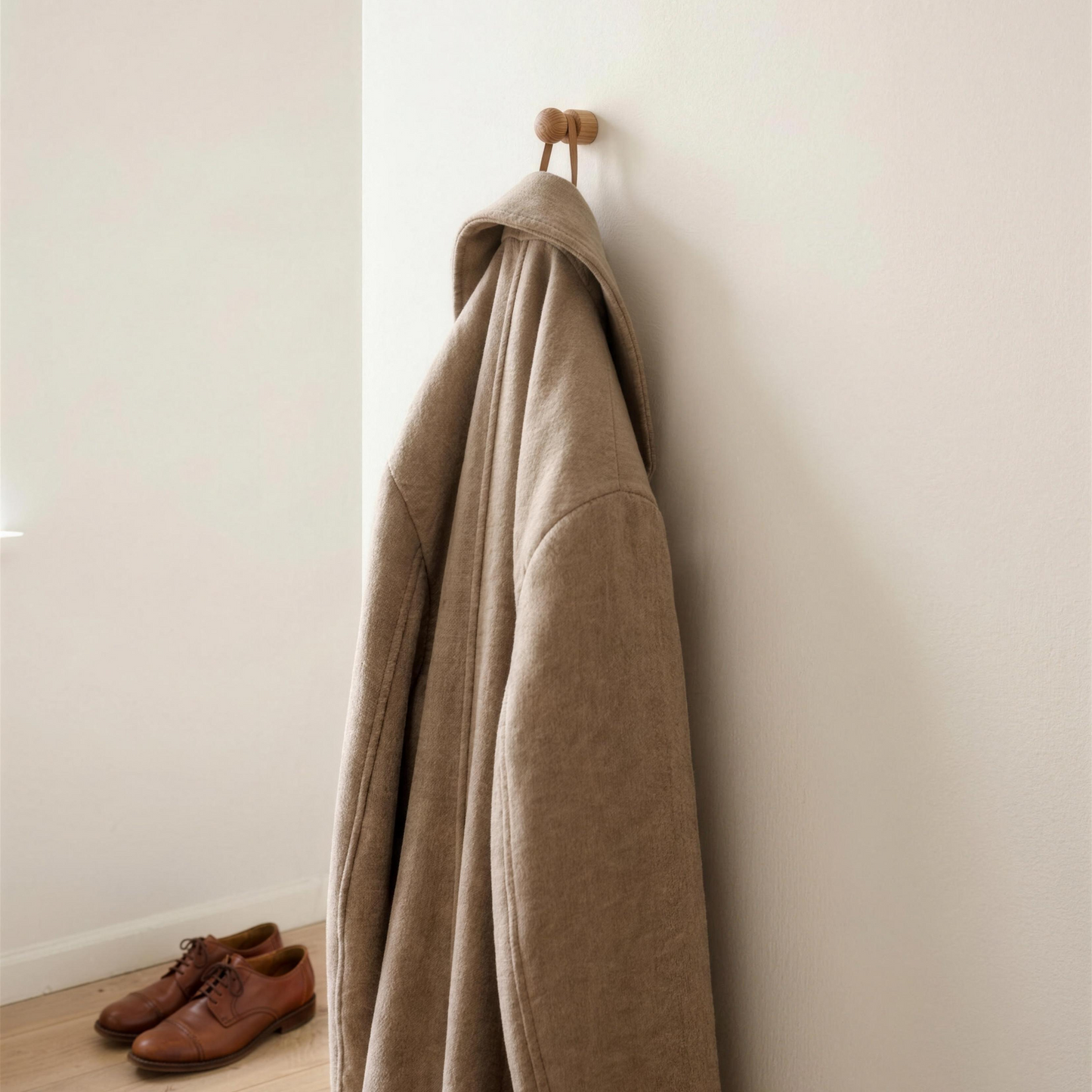 Anchor oak wall hook holding a beige wool coat in a Copenhagen entryway