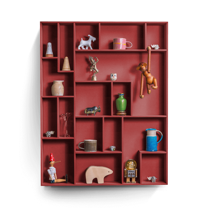 Decorative wall shelf with playful compartments displaying various items.