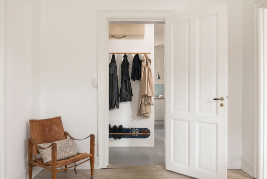 Small Copenhagen entryway with a wall-mounted shoe rack, coats on a peg rail, and a clear floor