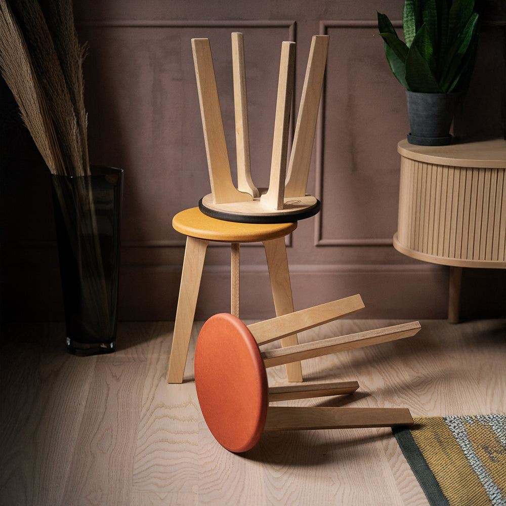 Three Bjørk stools in orange, black and yellow Valchromat® with birch plywood legs