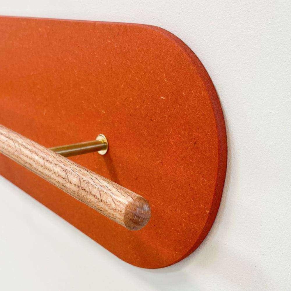 Primer plano del zapatero de pared Grounded en roble macizo, con protector de pared de Valchromat® naranja sobre una pared blanca