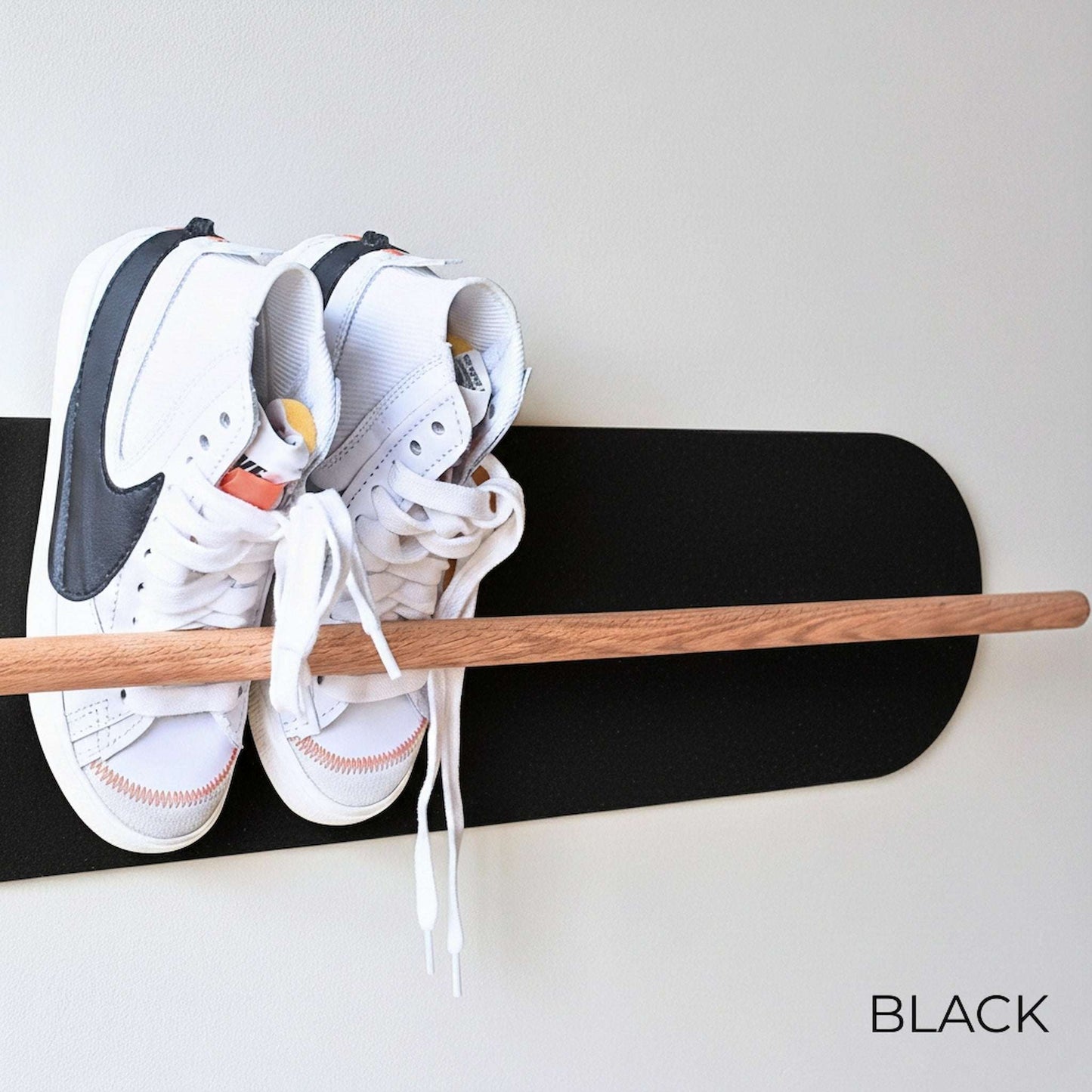 White Nike sneakers on a wooden Shoe  Shelf with Black wall protector against a white wall.