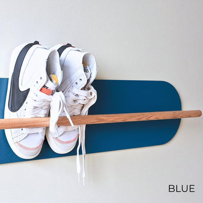 White Nike sneakers on a wooden Shoe  Shelf with Blue wall protector against a white wall.