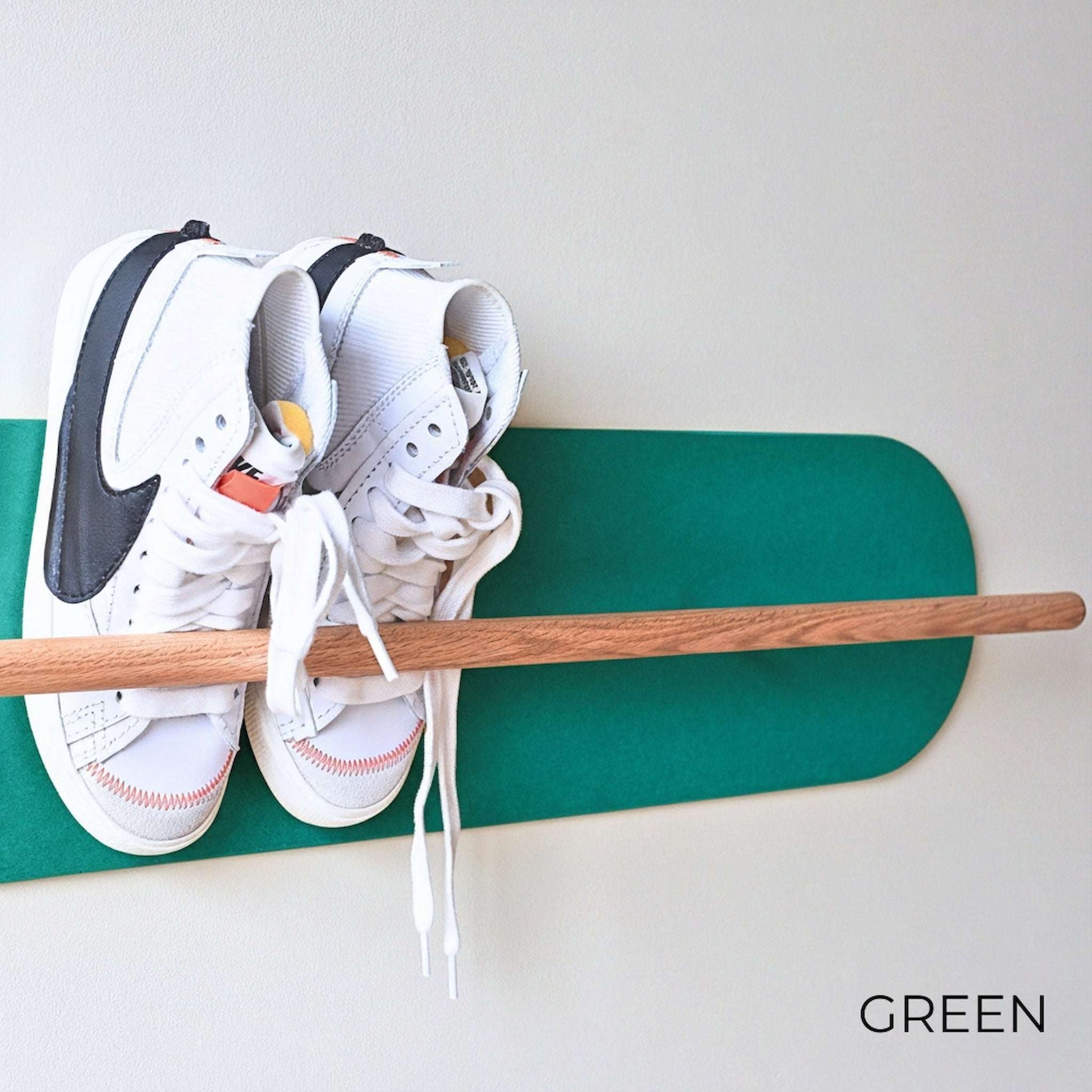 White Nike sneakers on a wooden Shoe  Shelf with Green wall protector against a white wall.