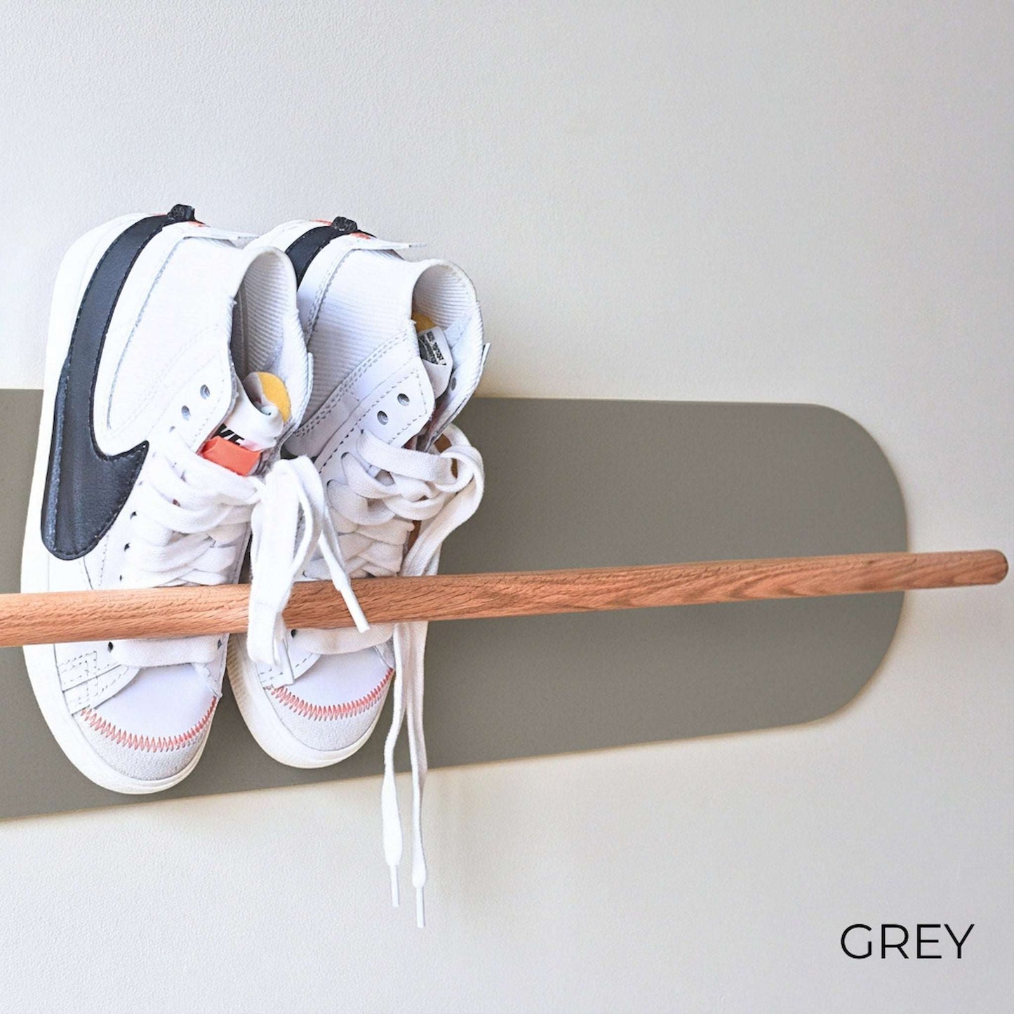 White Nike sneakers on a wooden Shoe  Shelf with Grey wall protector against a white wall.