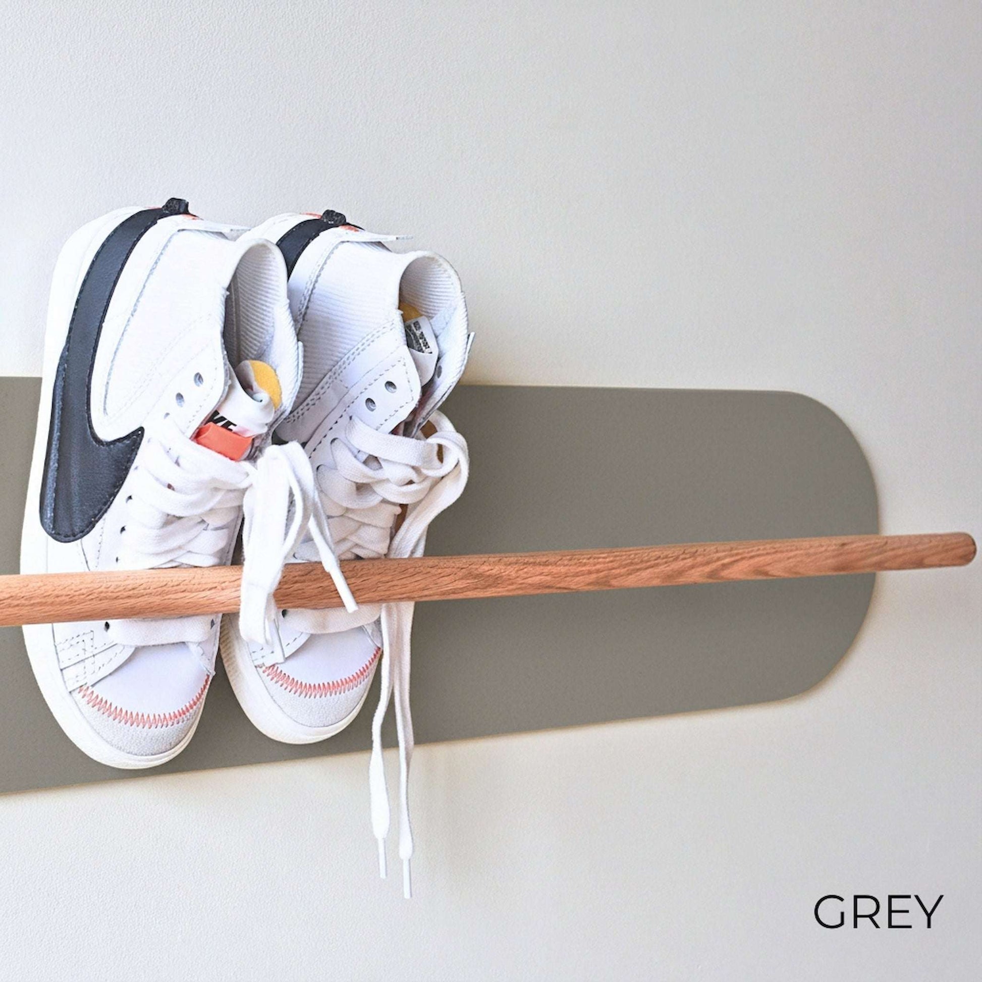 White Nike sneakers on a wooden Shoe  Shelf with Grey wall protector against a white wall.