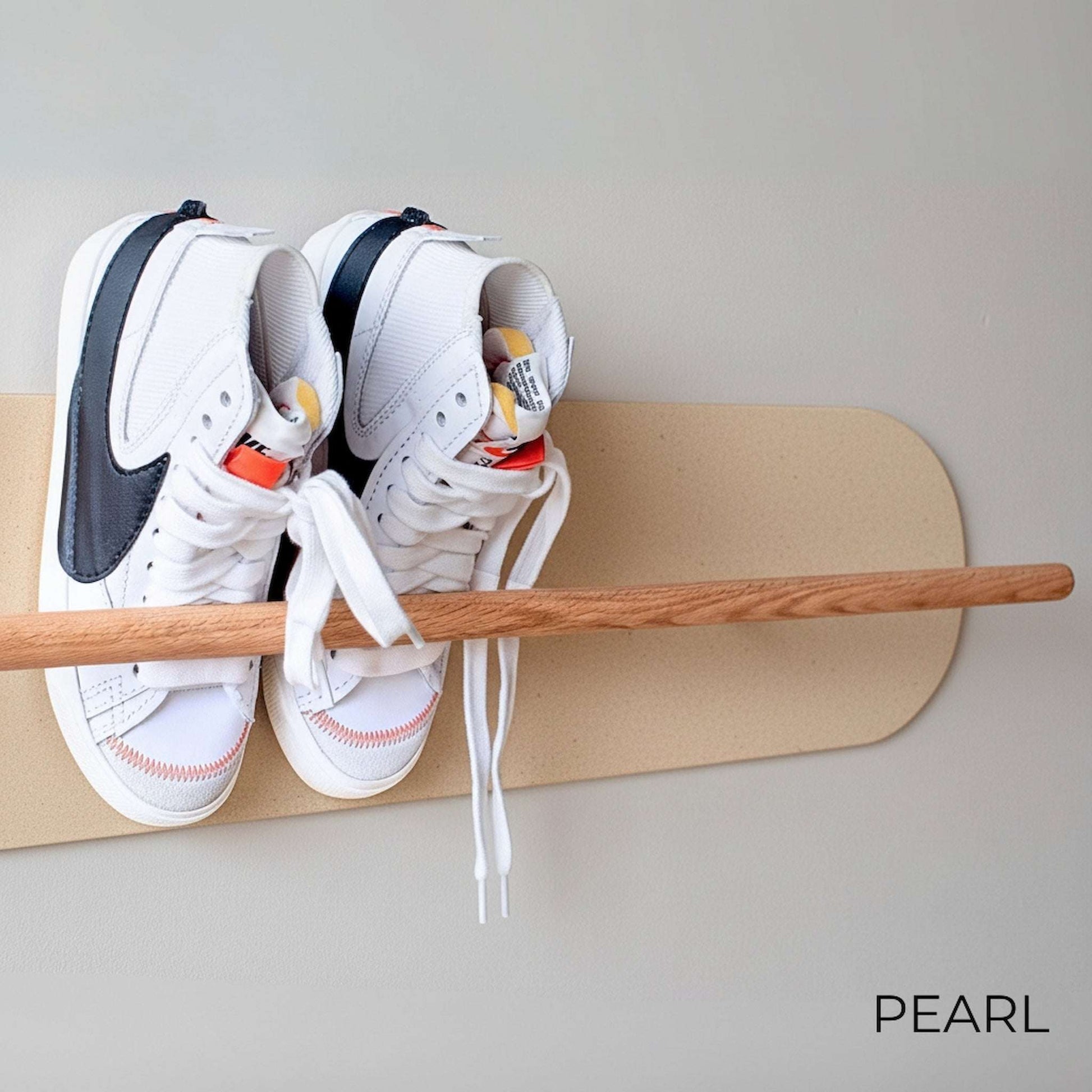 White Nike sneakers on a wooden Shoe  Shelf with White Pearl wall protector against a white wall.