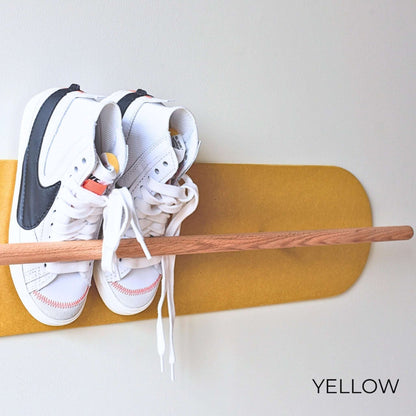 White Nike sneakers on a wooden Shoe  Shelf with yellow wall protector against a white wall.