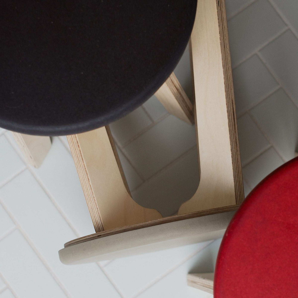 modern birch stool with black and red seats and natural wood frame on tiled floor
