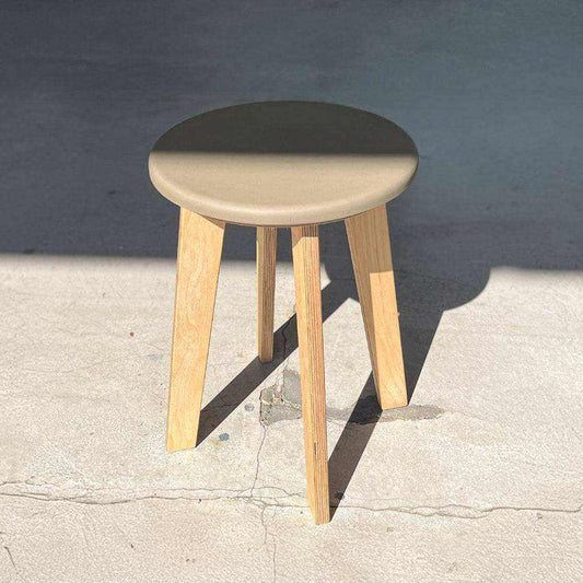 Bjørk Regular stool with Khaki Valchromat seat and wooden legs in natural light.