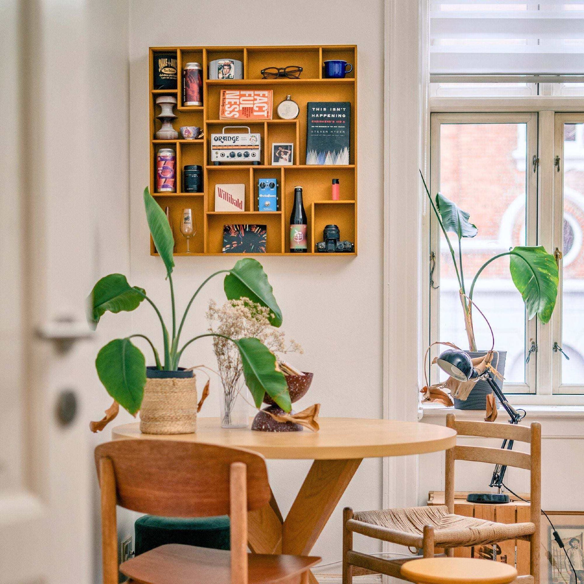 NicNac Timeless Box Shelf in yellow, wall-mounted in a dining room above a round table, styled with books and collectibles