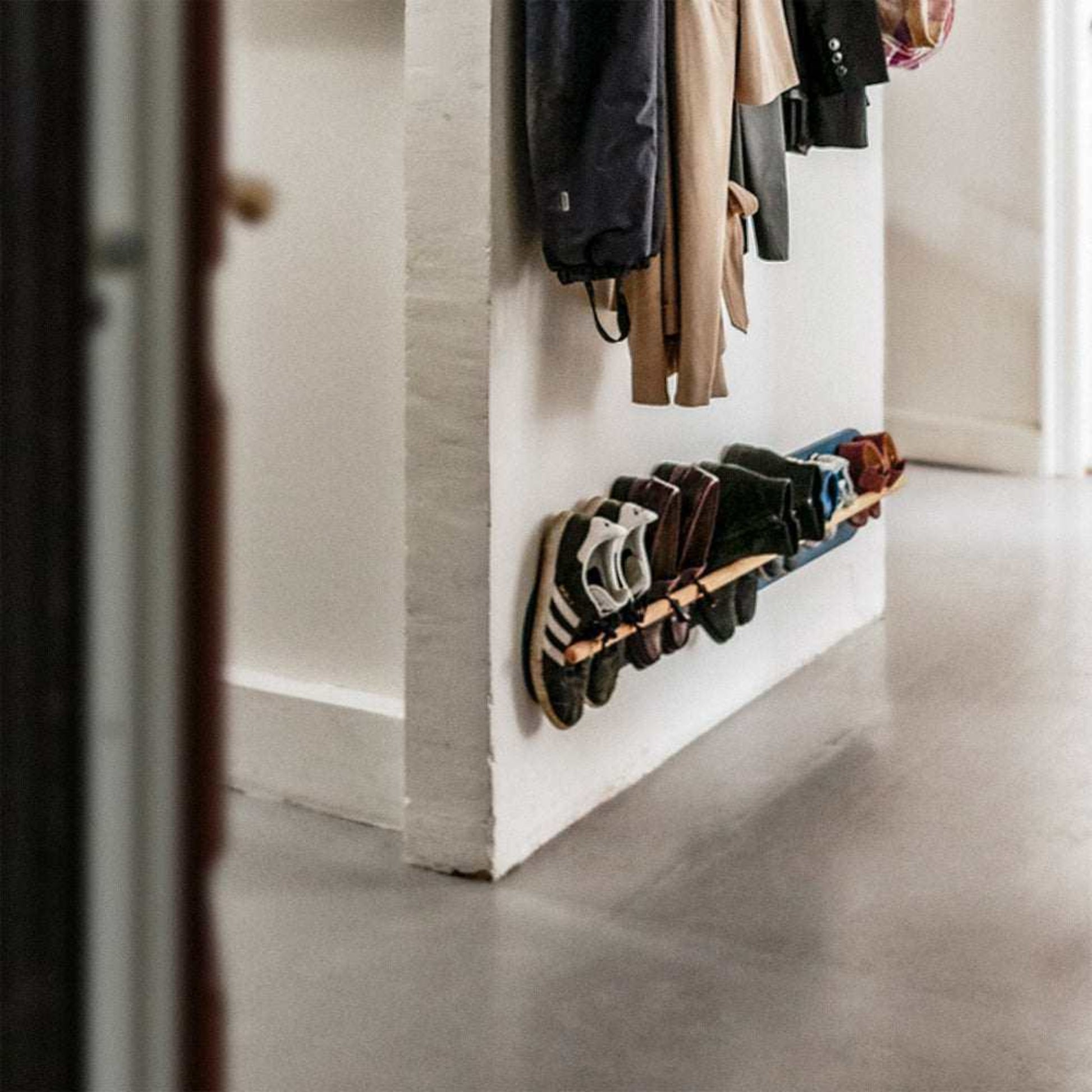 Grounded wall-mounted shoe rack in a Copenhagen apartment hallway, slim floating design in solid oak