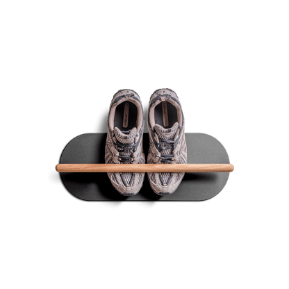 Minimalist space saving shoe rack mounted on wall holding a pair of sneakers.