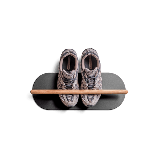 Minimalist space saving shoe rack mounted on wall holding a pair of sneakers.