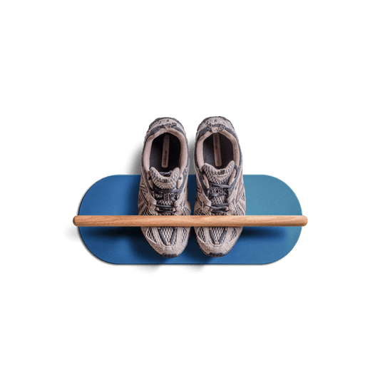 Minimalist space saving shoe rack in blue with wooden bar holding a pair of sneakers