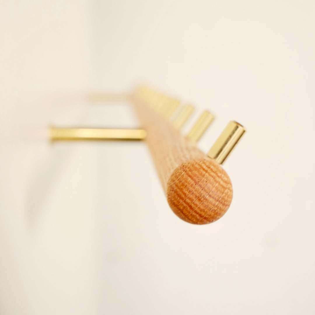 Solid oak wall-mounted coat rack with brass hooks and elegant design.